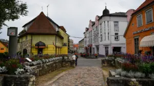 Vaizdingas istorinio miesto centras su tradicine architektūra, gėlėmis ir akmenimis grįsta gatve.